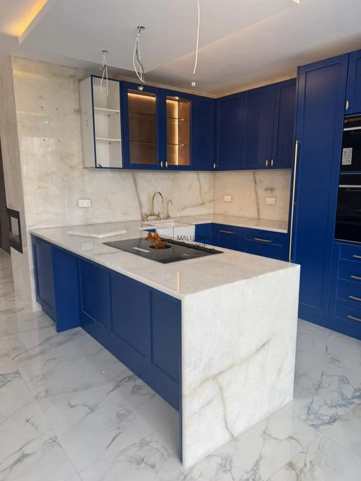 Cristallo quartzite waterfall island and backsplash with navy blue cabinets