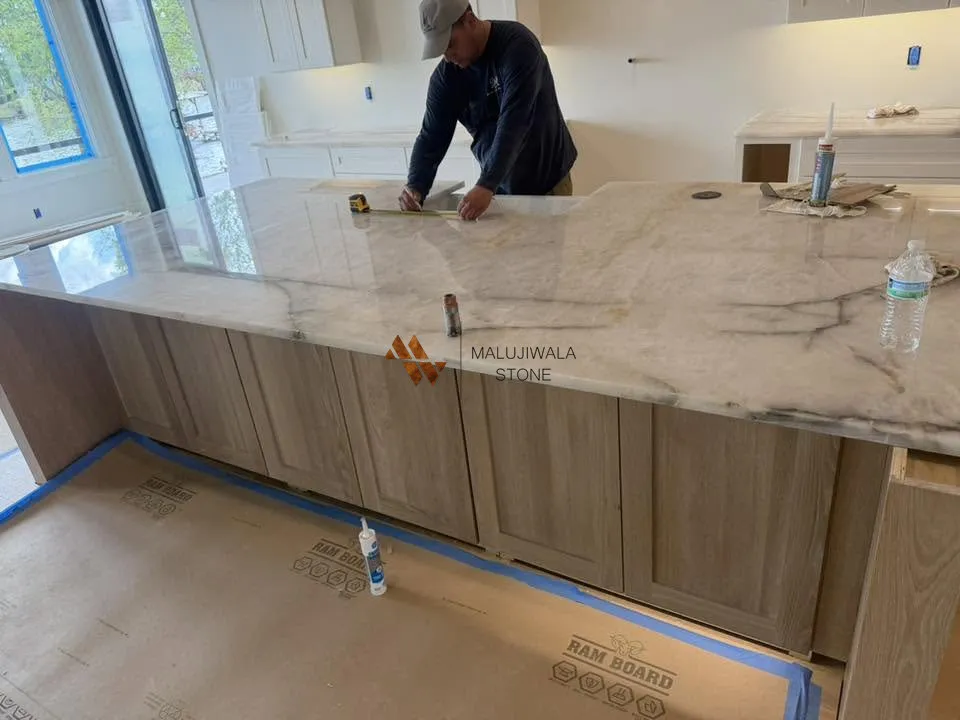 Installer setting a long Cristallo quartzite countertop on white oak cabinets