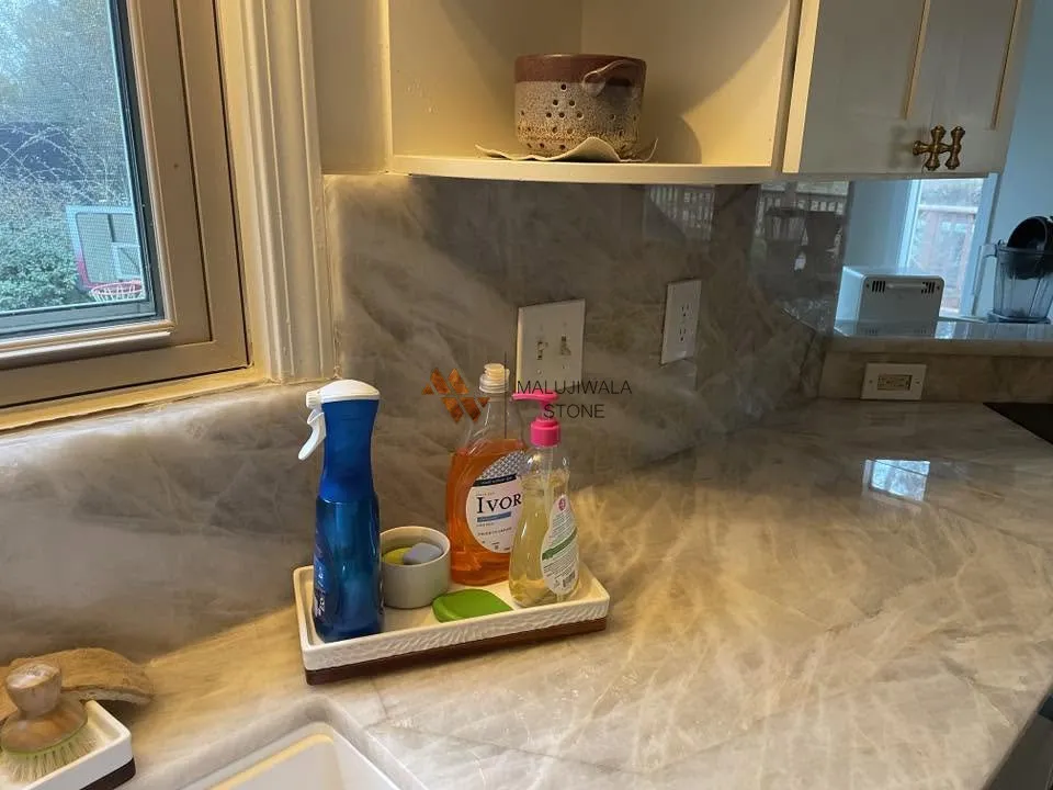 Cristallo quartzite countertop and backsplash under warm cabinet lighting