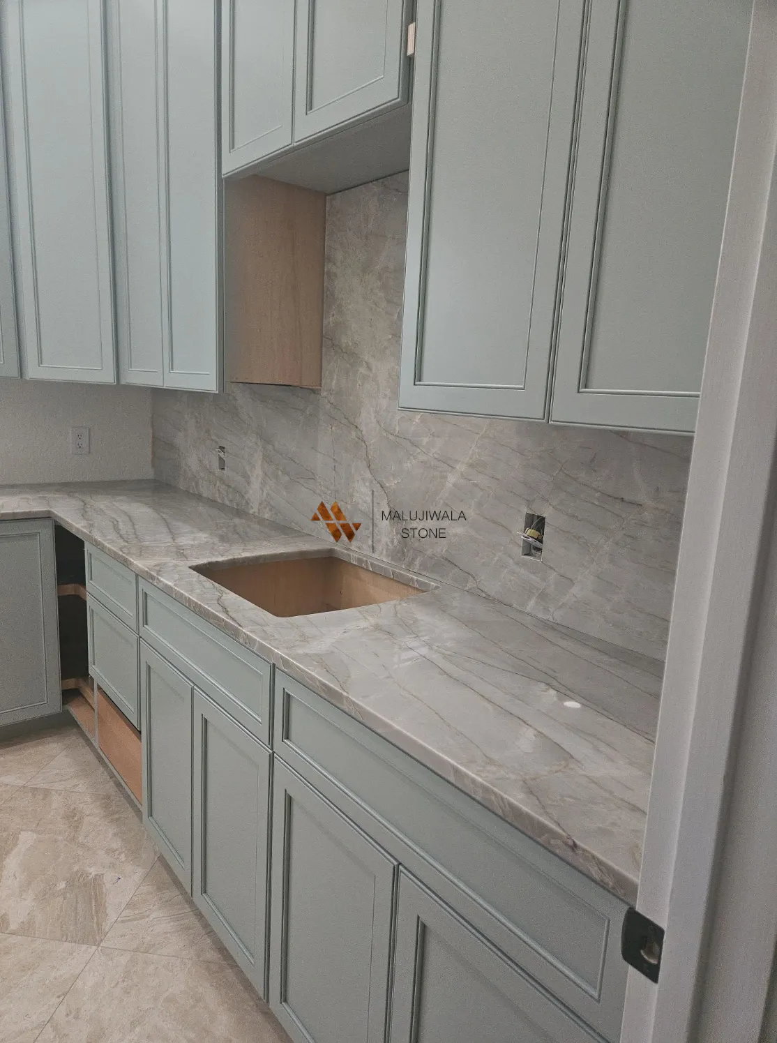 Taj Mahal quartzite countertop and full-height backsplash with sage green cabinets