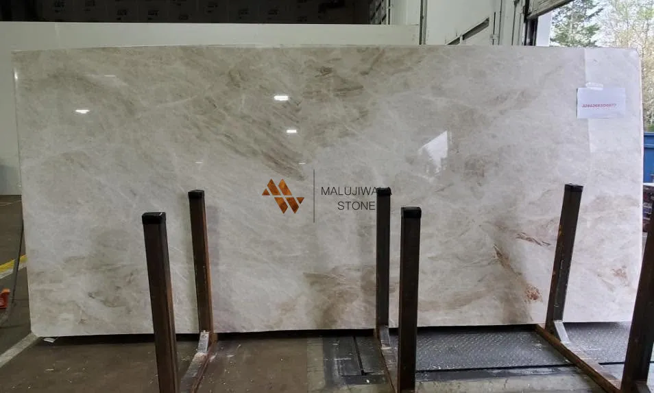 Polished Taj Mahal quartzite slab backsplash behind a kitchen faucet